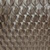 Zbliżenie na wypukłą strukturę płyty węglowej do kuchni o metalicznym charakterze i powtarzalnym wzorze geometrycznym.